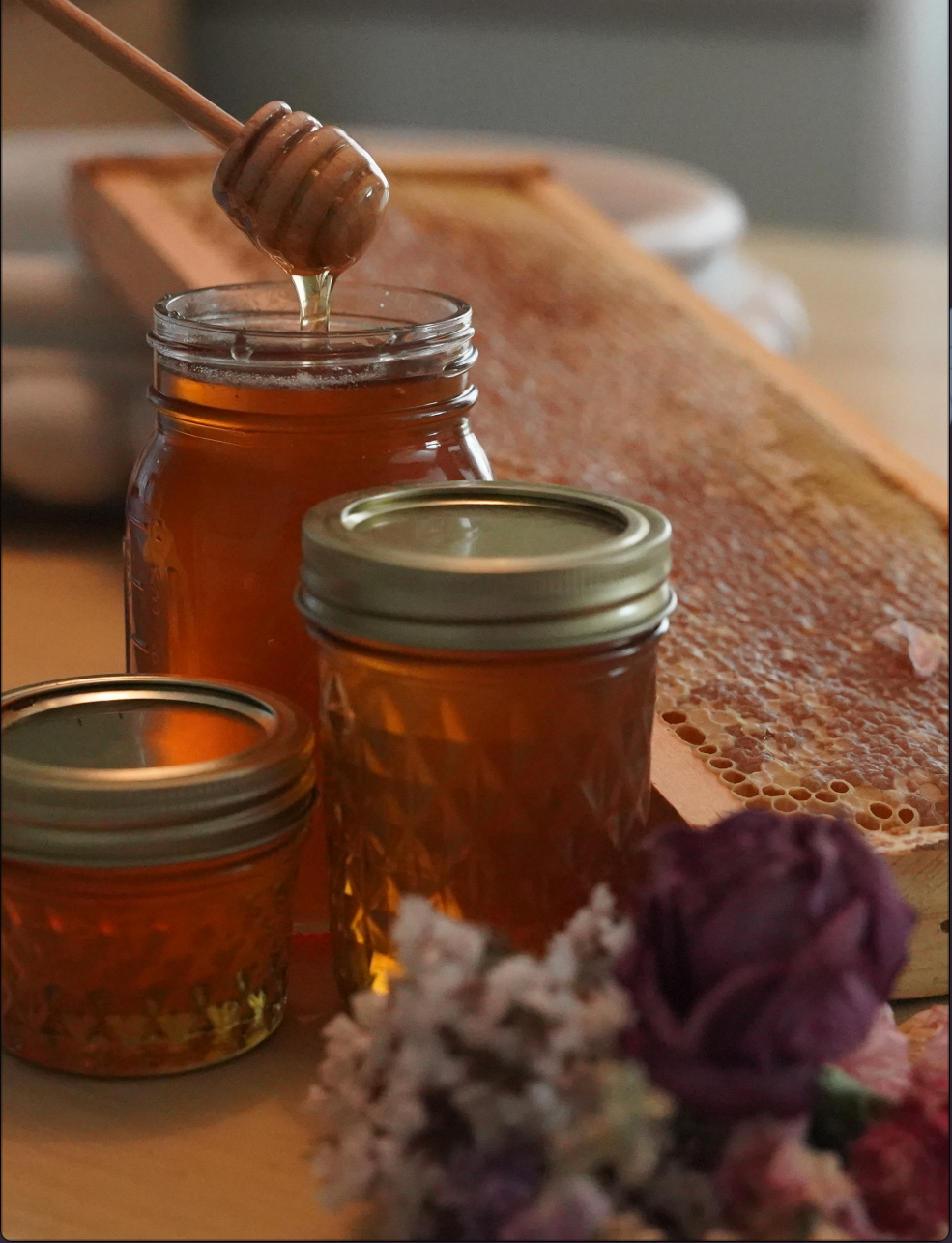 A jar of RussBee raw honey with a wooden honey dipper